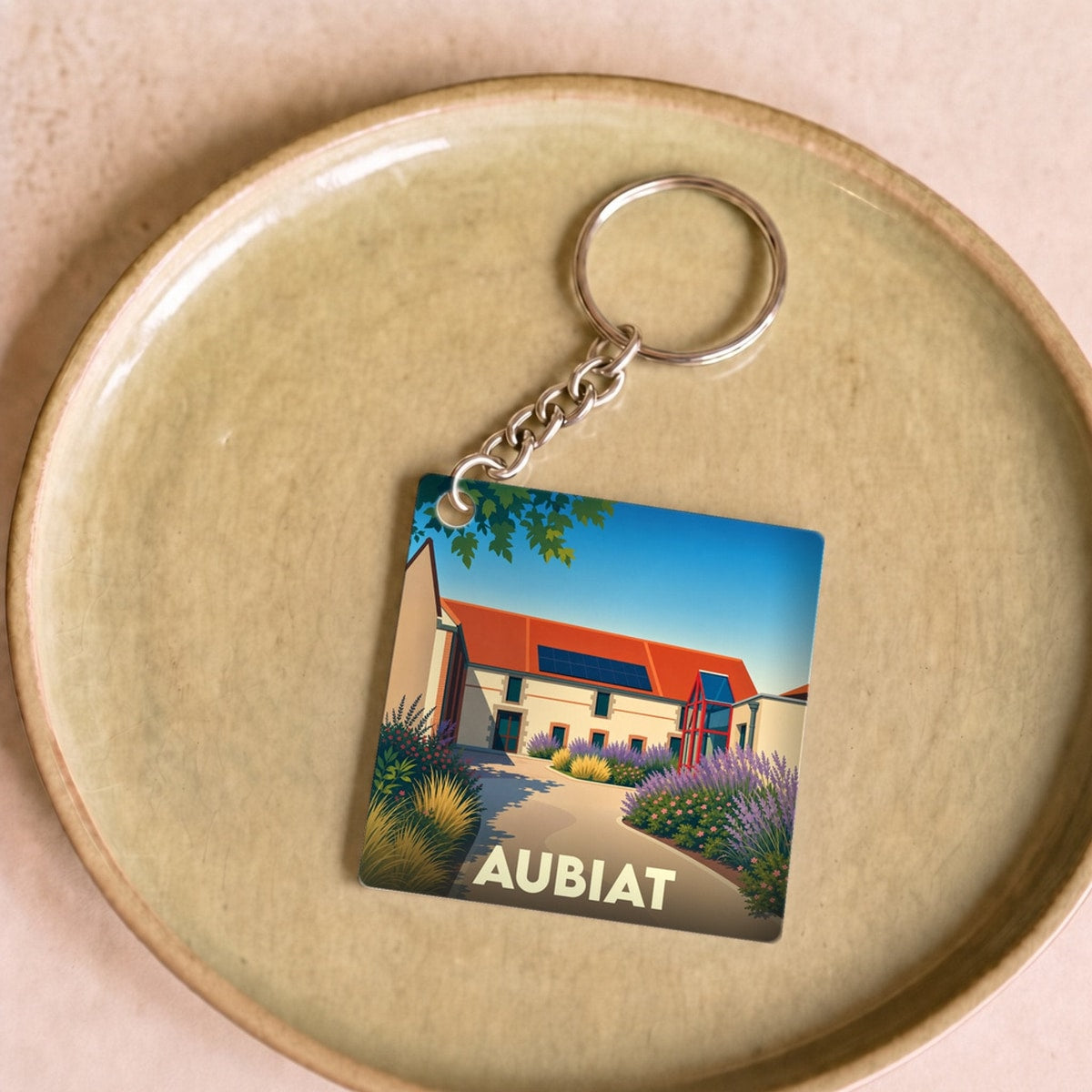 Porte-clés souvenir de la ville de Aubiat avec une illustration stylisée et colorée.