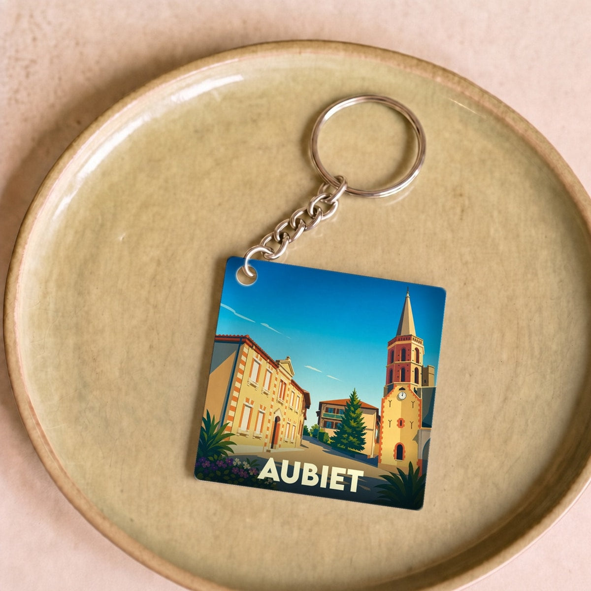 Porte-clés souvenir de la ville d'Aubiet avec une illustration stylisée.