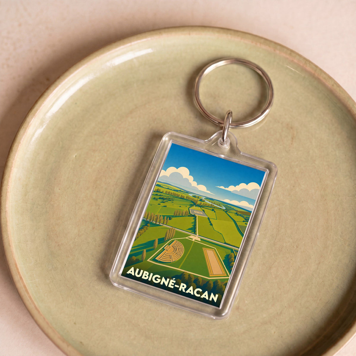 Porte-clés souvenir de la ville d'Aubigné-Racan avec une illustration stylisée de son site archéologique.