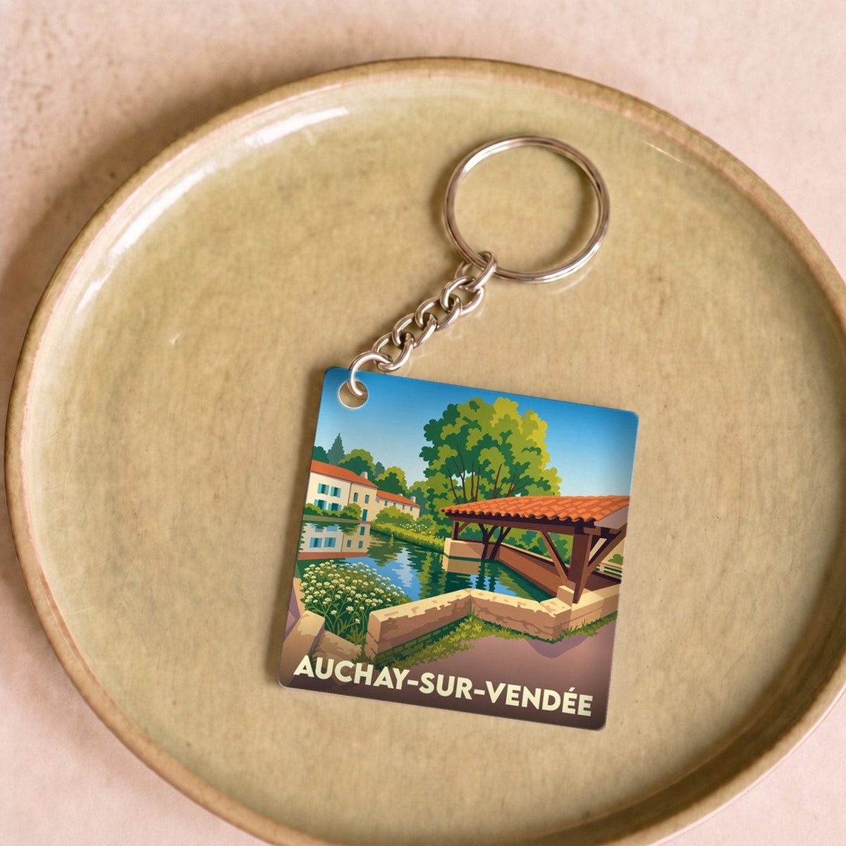 Porte-clés souvenir de la ville de Auchay-sur-Vendée avec une illustration stylisée d'un paysage local.