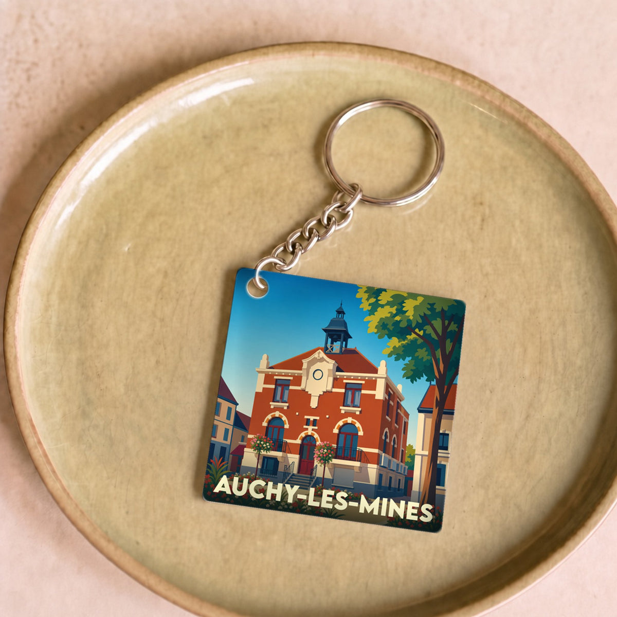 Porte-clés souvenir de la ville d'Auchy-les-Mines avec une illustration stylisée de son hôtel de ville.