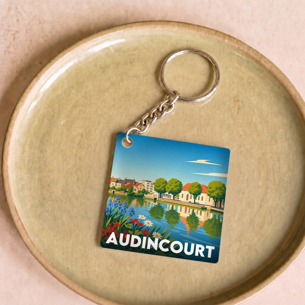 Porte-clés souvenir de la ville d'Audincourt avec une illustration stylisée.
