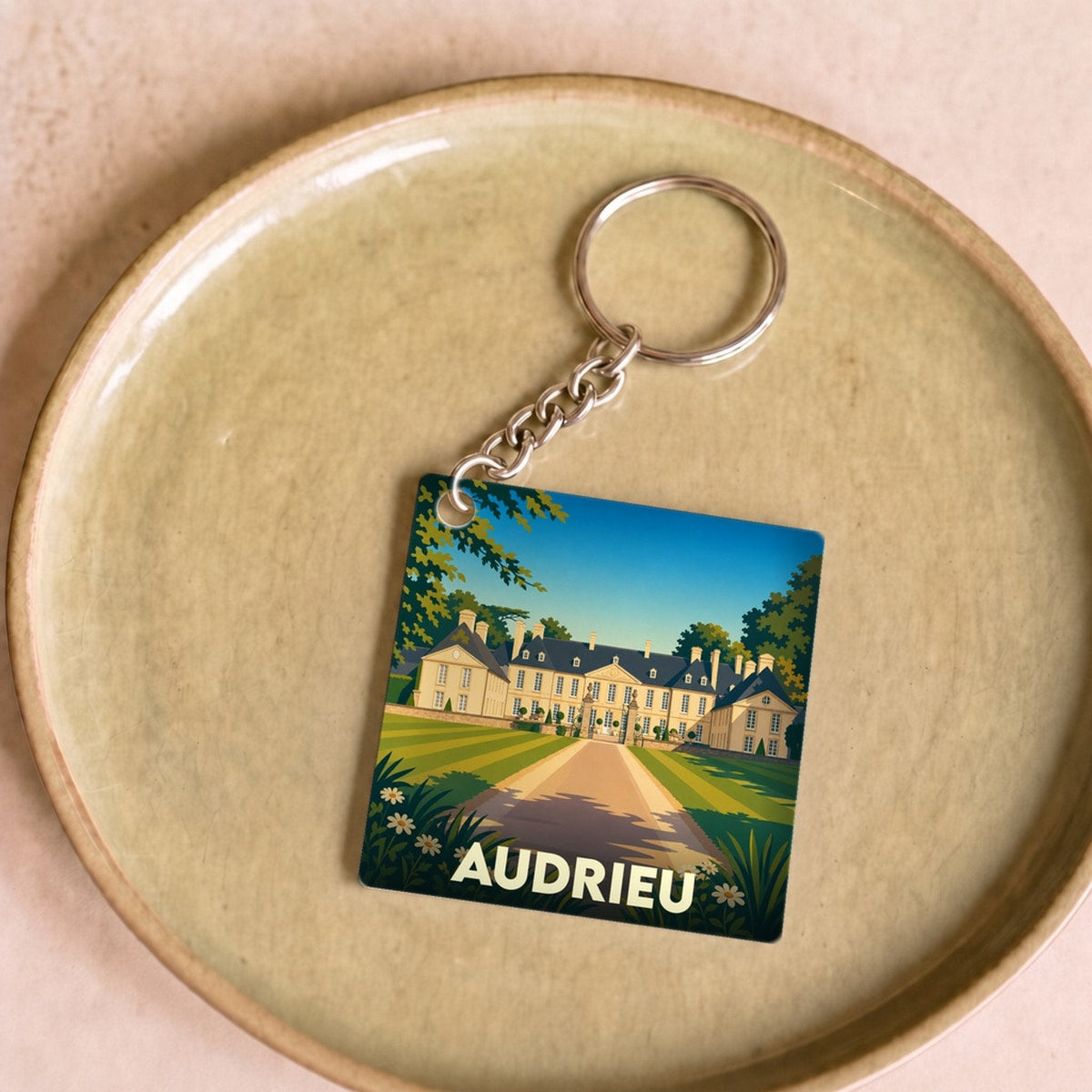 Porte-clés souvenir de la ville d'Audrieu avec une illustration stylisée d'un château.