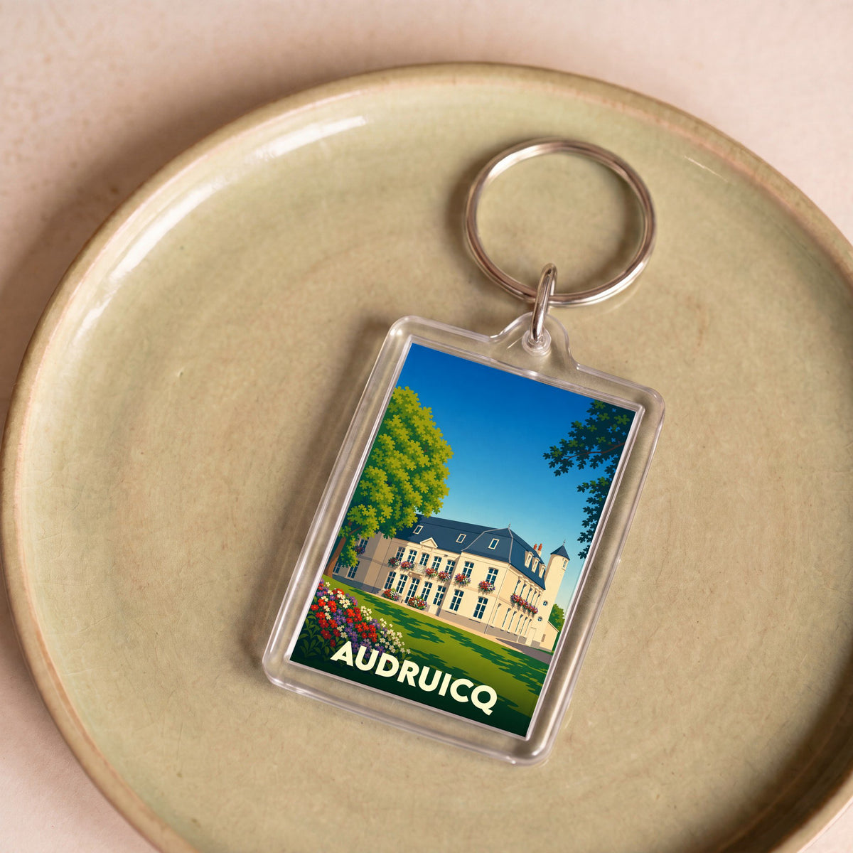 Porte-clés souvenir de la ville de Audruicq avec une illustration stylisée d'un manoir.