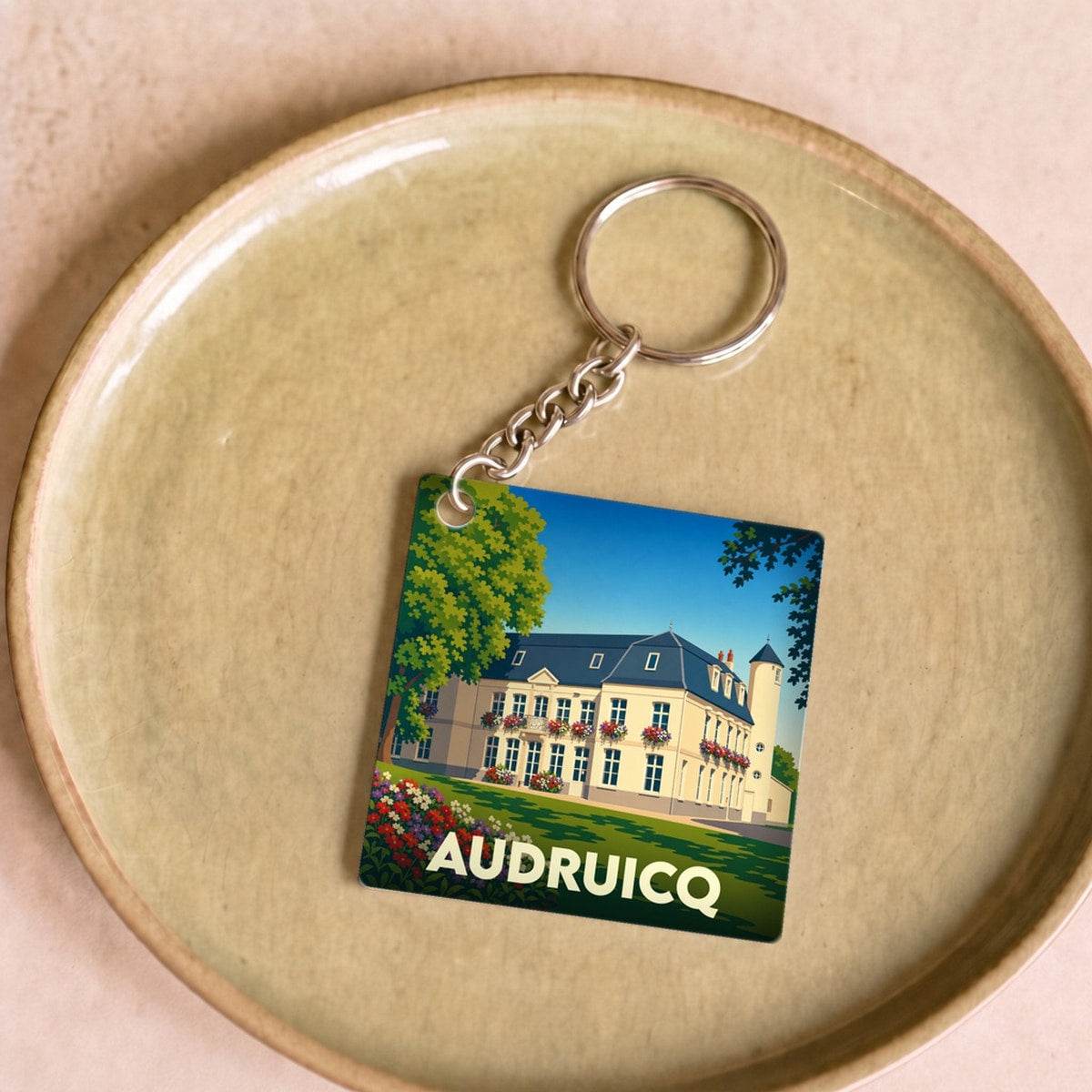 Porte-clés souvenir de la ville d'Audruicq avec une illustration stylisée de son hôtel de ville.