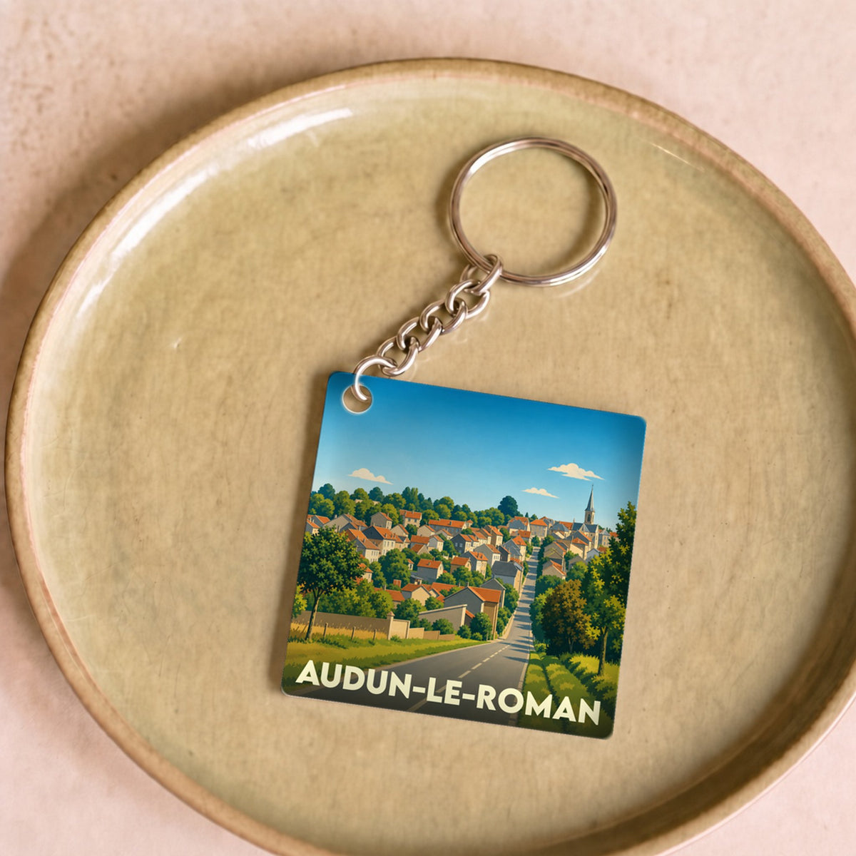 Porte-clés souvenir de la ville de Audun-le-Roman avec une illustration stylisée d'un paysage urbain.