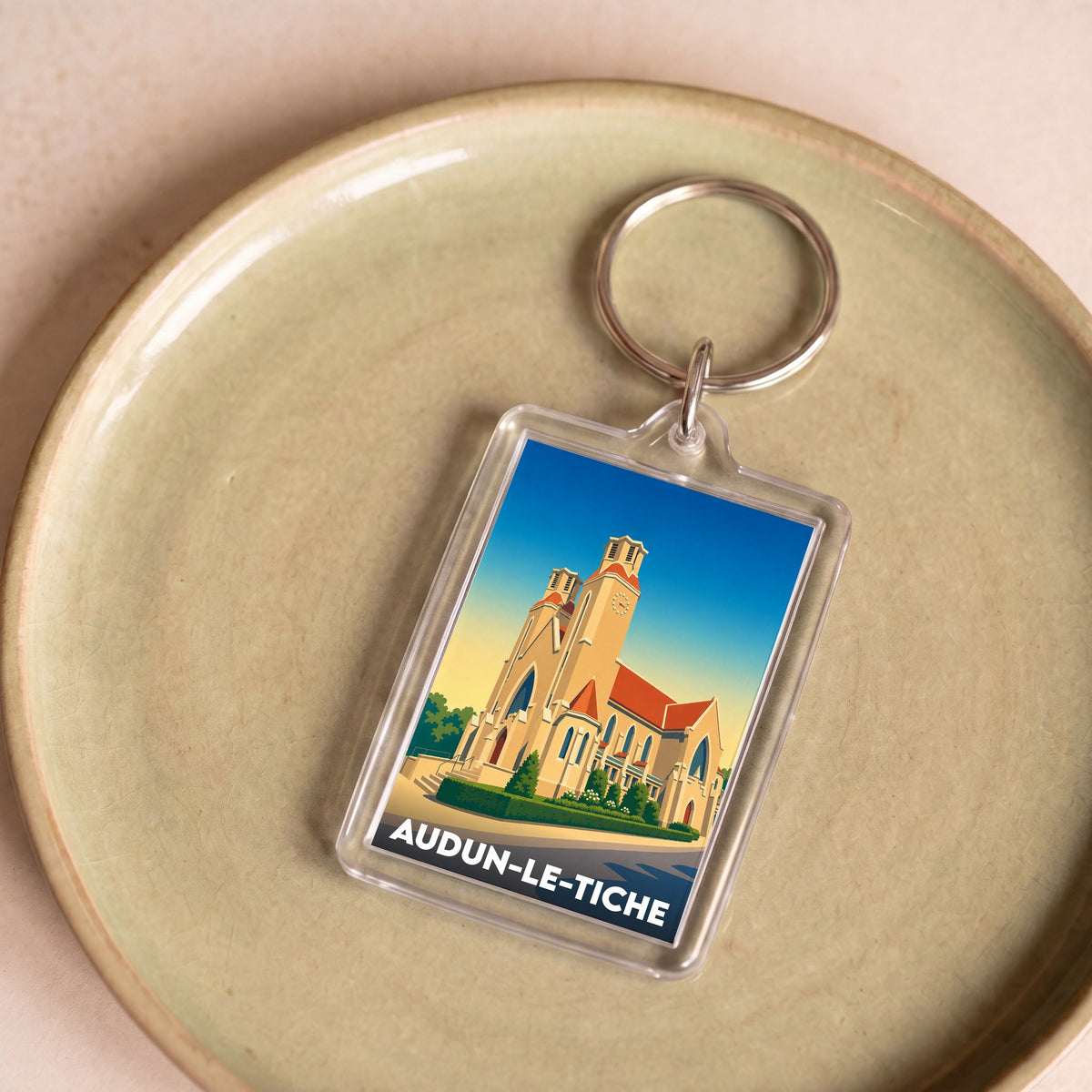 Porte-clés souvenir de la ville de Audun-le-Tiche avec une illustration stylisée de son église.