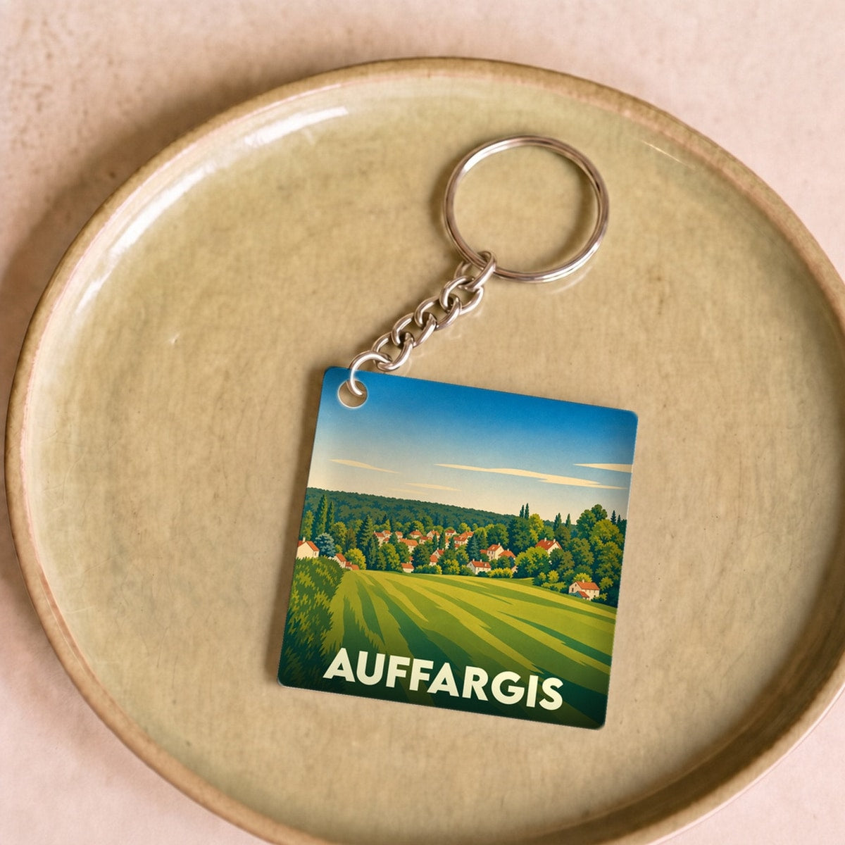 Porte-clés souvenir de la ville d'Auffargis avec une illustration stylisée de son paysage rural.