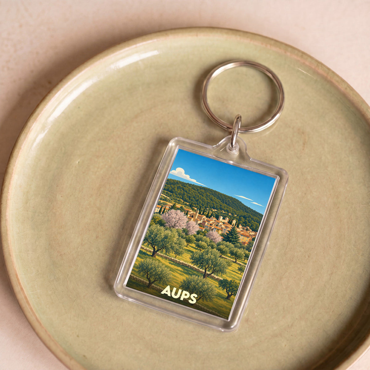 Porte-clés souvenir de la ville de Aups avec une illustration stylisée.