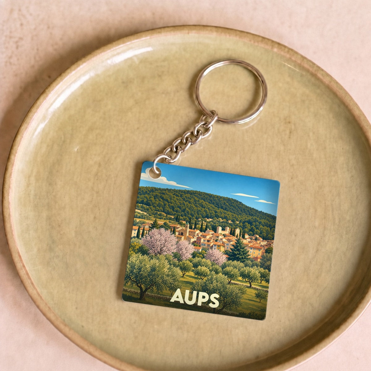 Porte-clés souvenir de la ville de Aups avec une illustration stylisée.