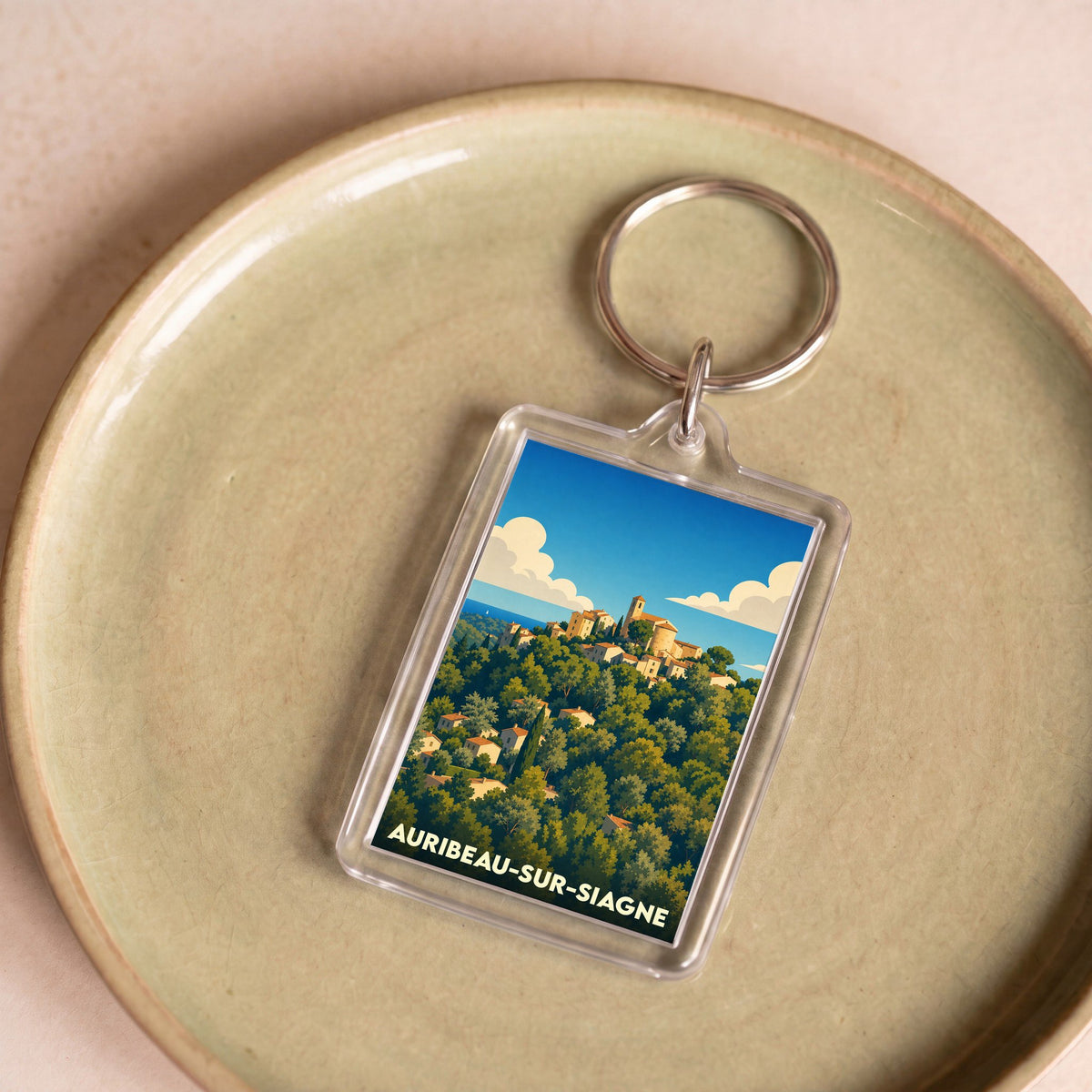 Porte-clés souvenir de la ville d'Auribeau-sur-Siagne avec une illustration stylisée du village perché.