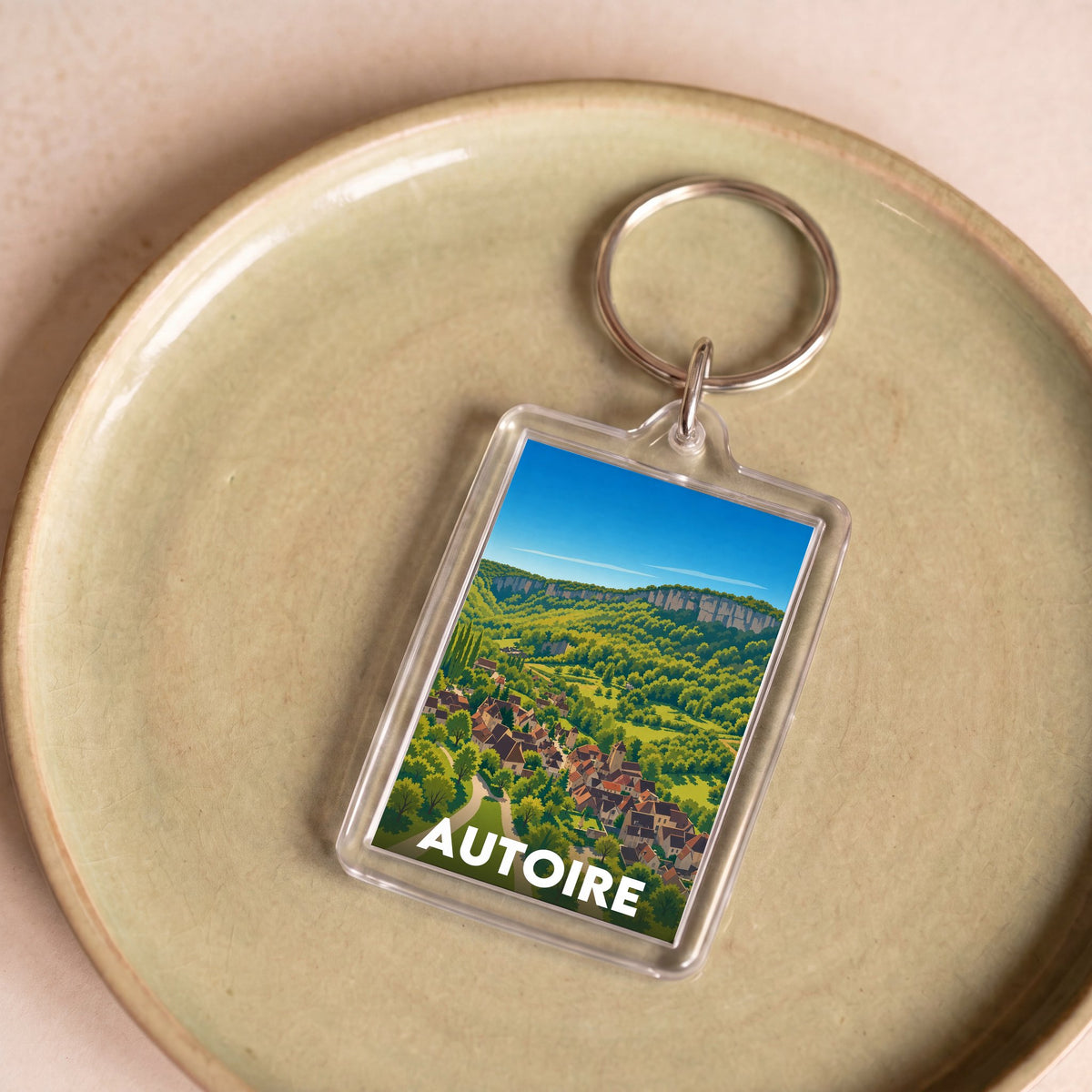 Porte-clés souvenir de la ville d'Autoire avec une illustration stylisée.
