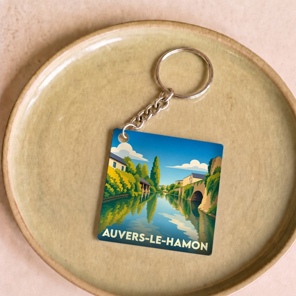 Porte-clés souvenir de la ville de Auvers-le-Hamon avec une illustration stylisée d'une rivière.