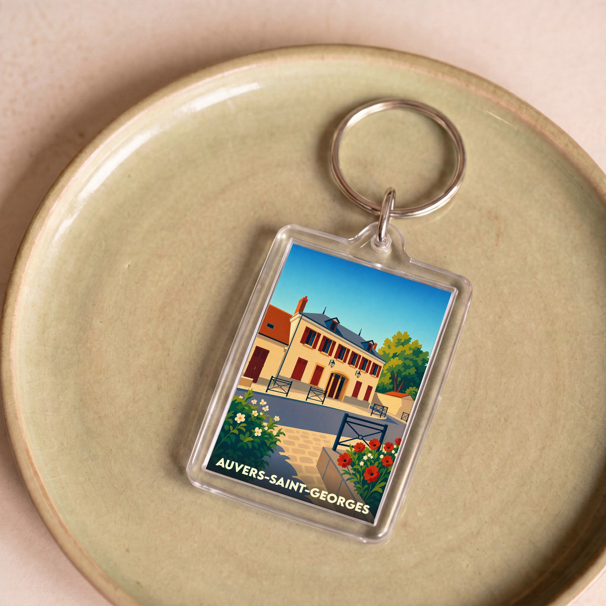 Porte-clés souvenir de la ville de Auvers-Saint-Georges avec une illustration stylisée d'un bâtiment historique.