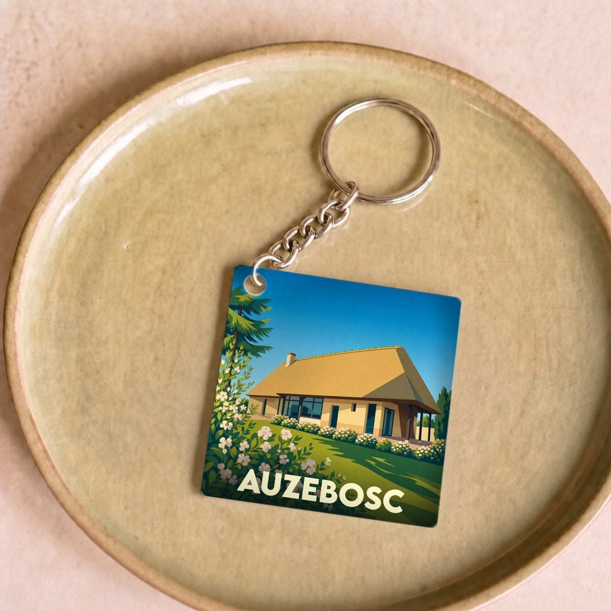 Porte-clés souvenir de la ville de Auzebosc avec une illustration stylisée.