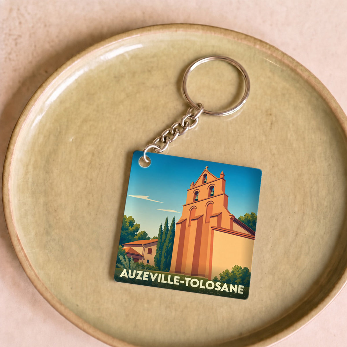 Porte-clés souvenir de la ville de Auzeville-Tolosane avec une illustration stylisée de son église.