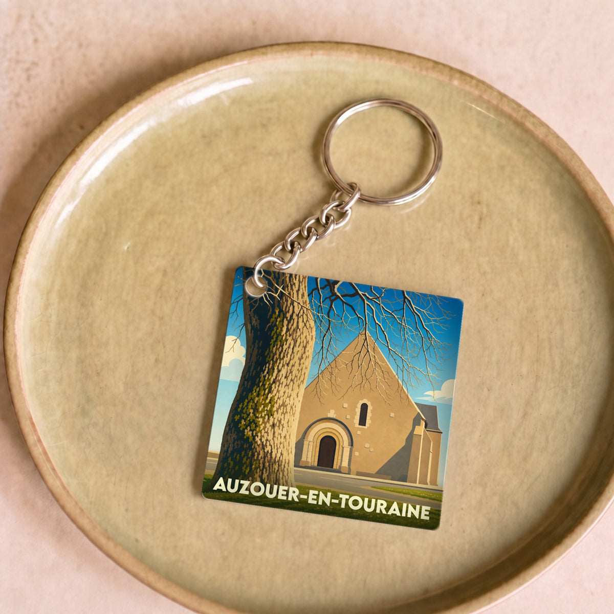 Porte-clés souvenir de la ville de Auzouer-en-Touraine avec une illustration stylisée.