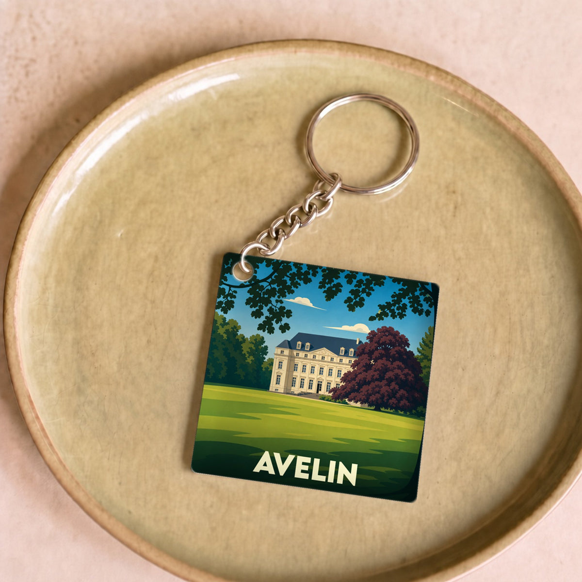 Porte-clés souvenir de la ville d'Avelin illustrant un château dans un parc verdoyant.