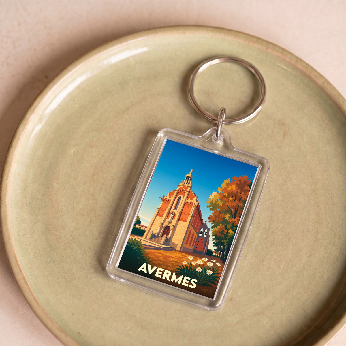 Porte-clés souvenir de la ville d'Avermes avec une illustration stylisée de son église sous un ciel bleu.