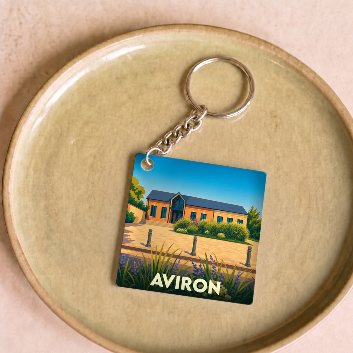 Porte-clés souvenir de la ville d'Aviron avec une illustration stylisée d'un bâtiment local.