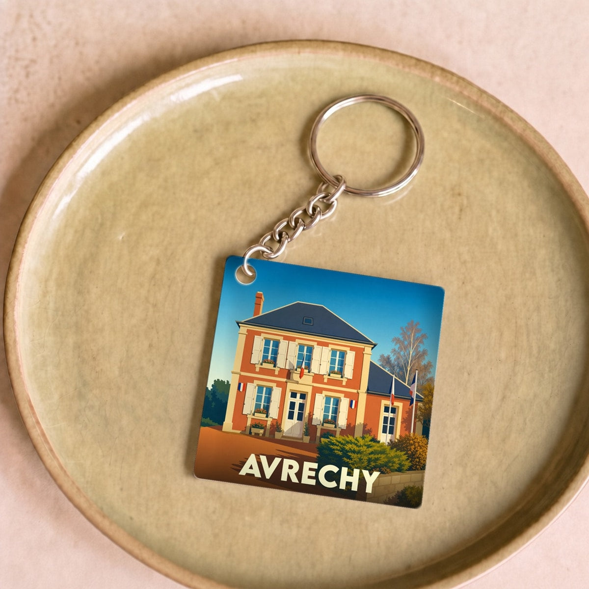 Porte-clés souvenir de la ville de Avrechy avec une illustration stylisée d'un bâtiment communal.