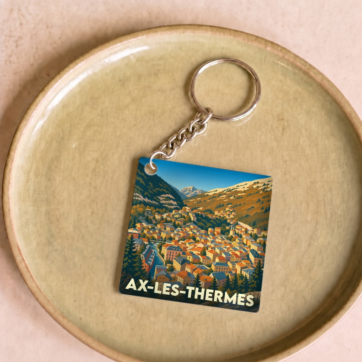 Porte-clés souvenir de la ville de Ax-les-Thermes avec une illustration stylisée.