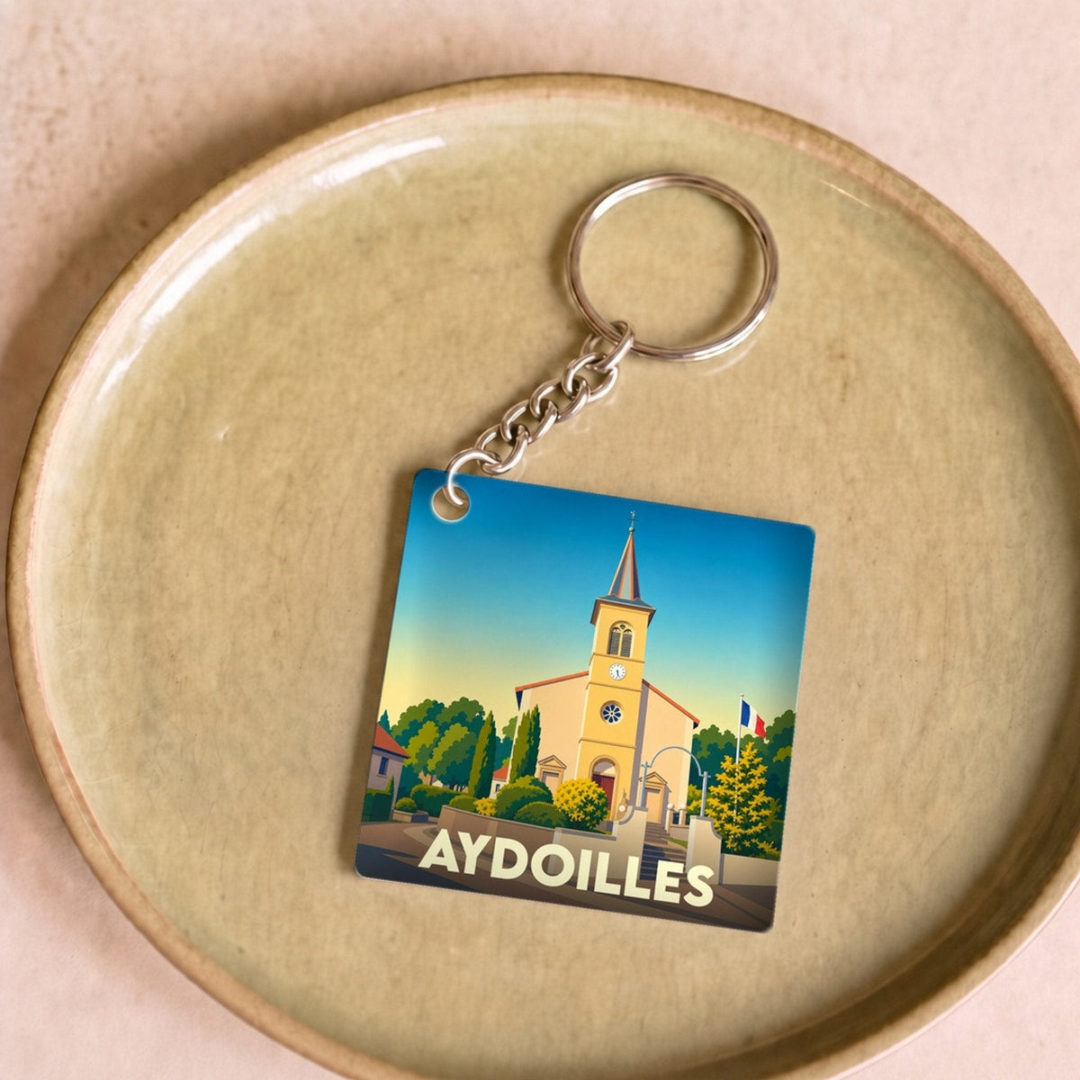 Porte-clés souvenir de la ville d'Aydoilles avec une illustration stylisée de son église.