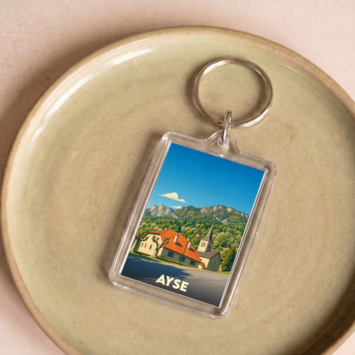 Porte-clés souvenir de la ville d'Ayse avec une illustration stylisée de ses paysages de montagne.