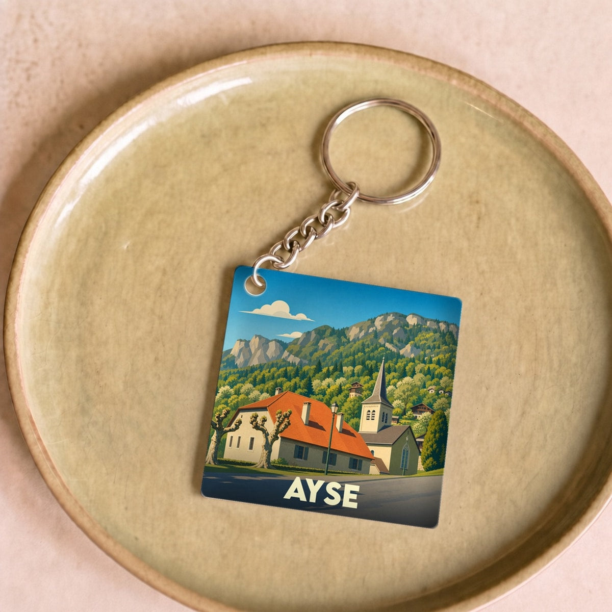 Porte-clés souvenir de la ville d'Ayse avec une illustration stylisée de ses paysages de montagne.