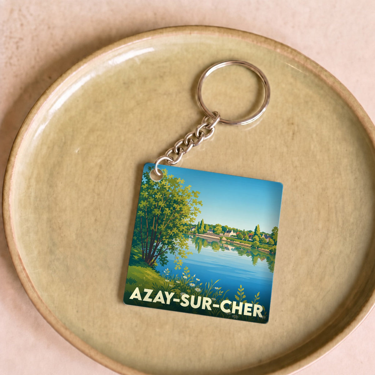 Porte-clés souvenir de la ville d'Azay-sur-Cher avec une illustration stylisée d'un bord de rivière.