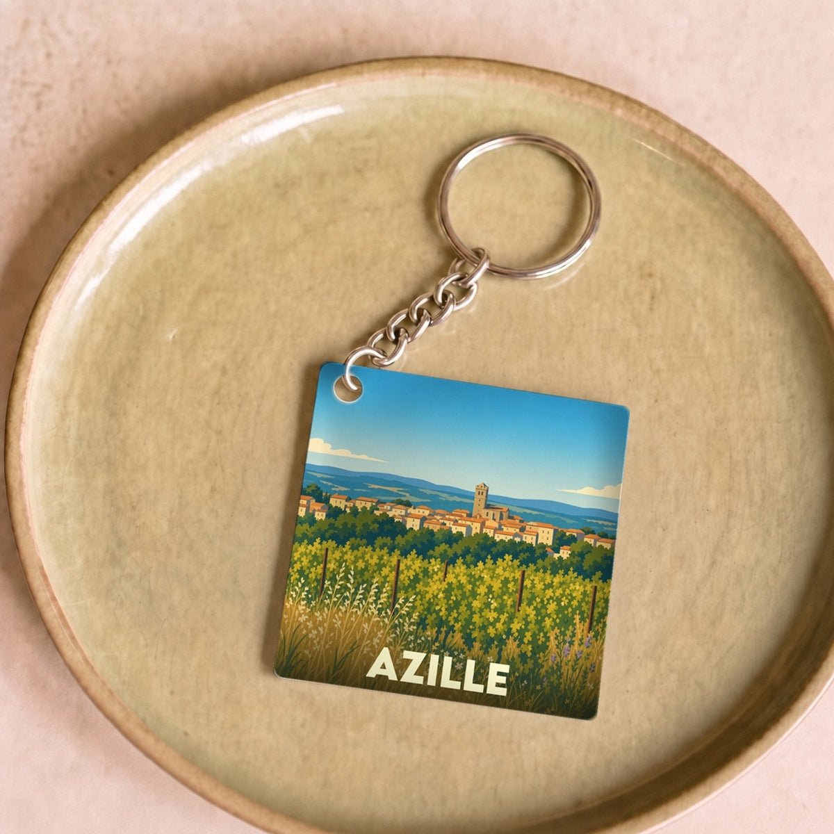 Porte-clés souvenir de la ville d'Azille avec une illustration stylisée de son paysage.