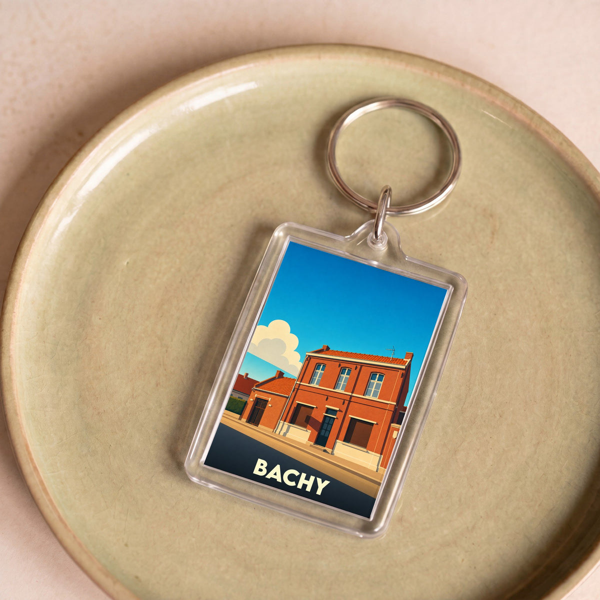 Porte-clés souvenir de la ville de Bachy avec une illustration stylisée d'un bâtiment en briques.