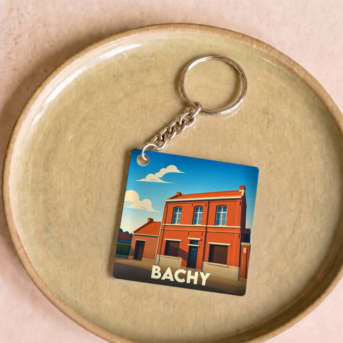 Porte-clés souvenir de la ville de Bachy avec une illustration stylisée d'un bâtiment en briques.