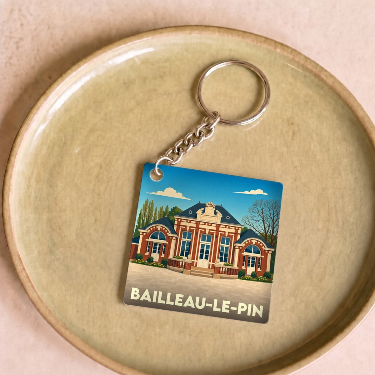 Porte-clés souvenir de la ville de Bailleau-le-Pin avec une illustration stylisée de sa mairie.