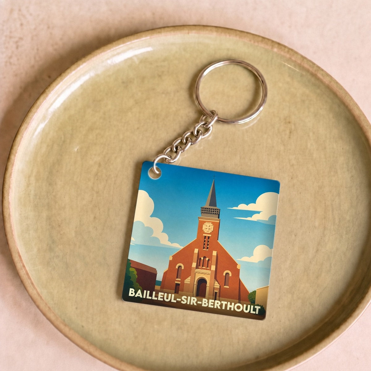 Porte-clés souvenir de la ville de Bailleul-Sir-Berthoult avec une illustration stylisée de son église.