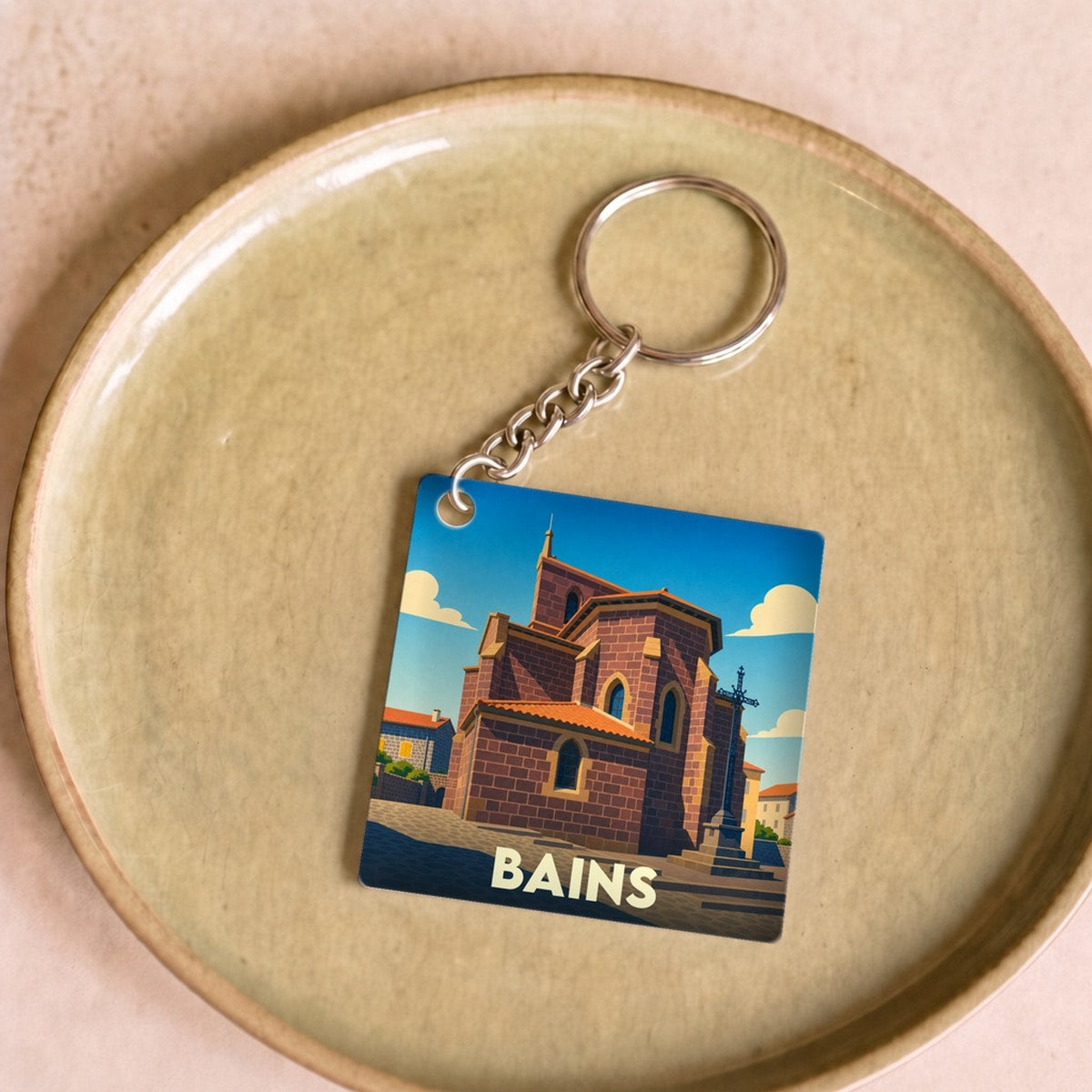 Porte-clés souvenir de la ville de Bains avec une illustration stylisée de son église.