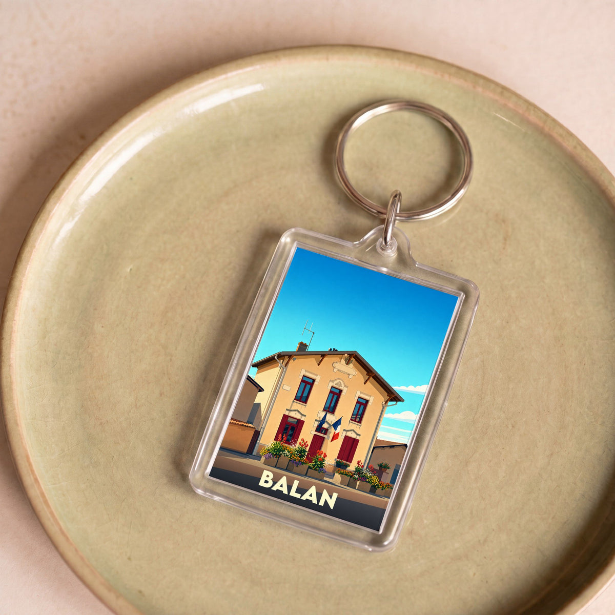 Porte-clés souvenir de la ville de Balan avec une illustration stylisée.