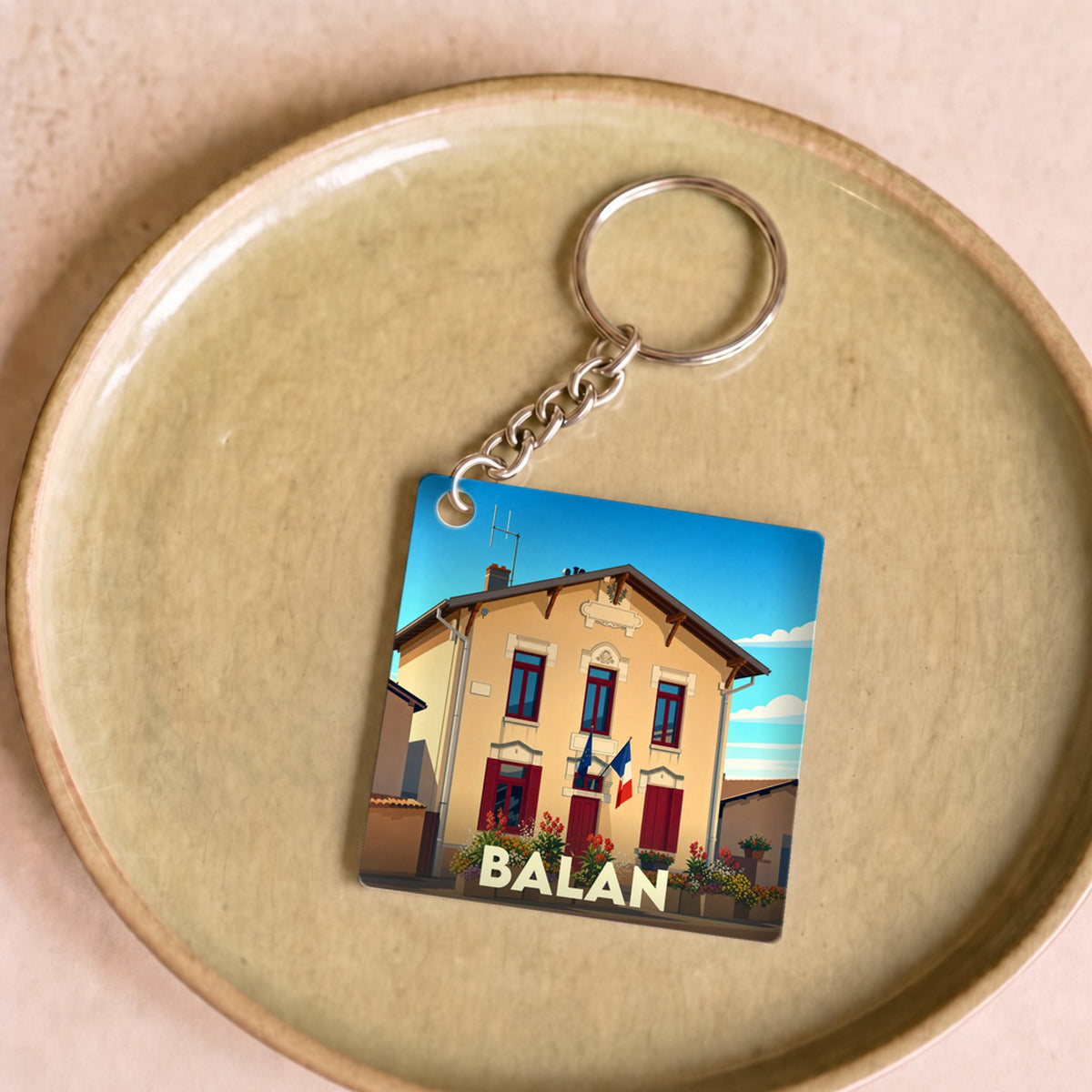 Porte-clés souvenir de la ville de Balan avec une illustration stylisée.