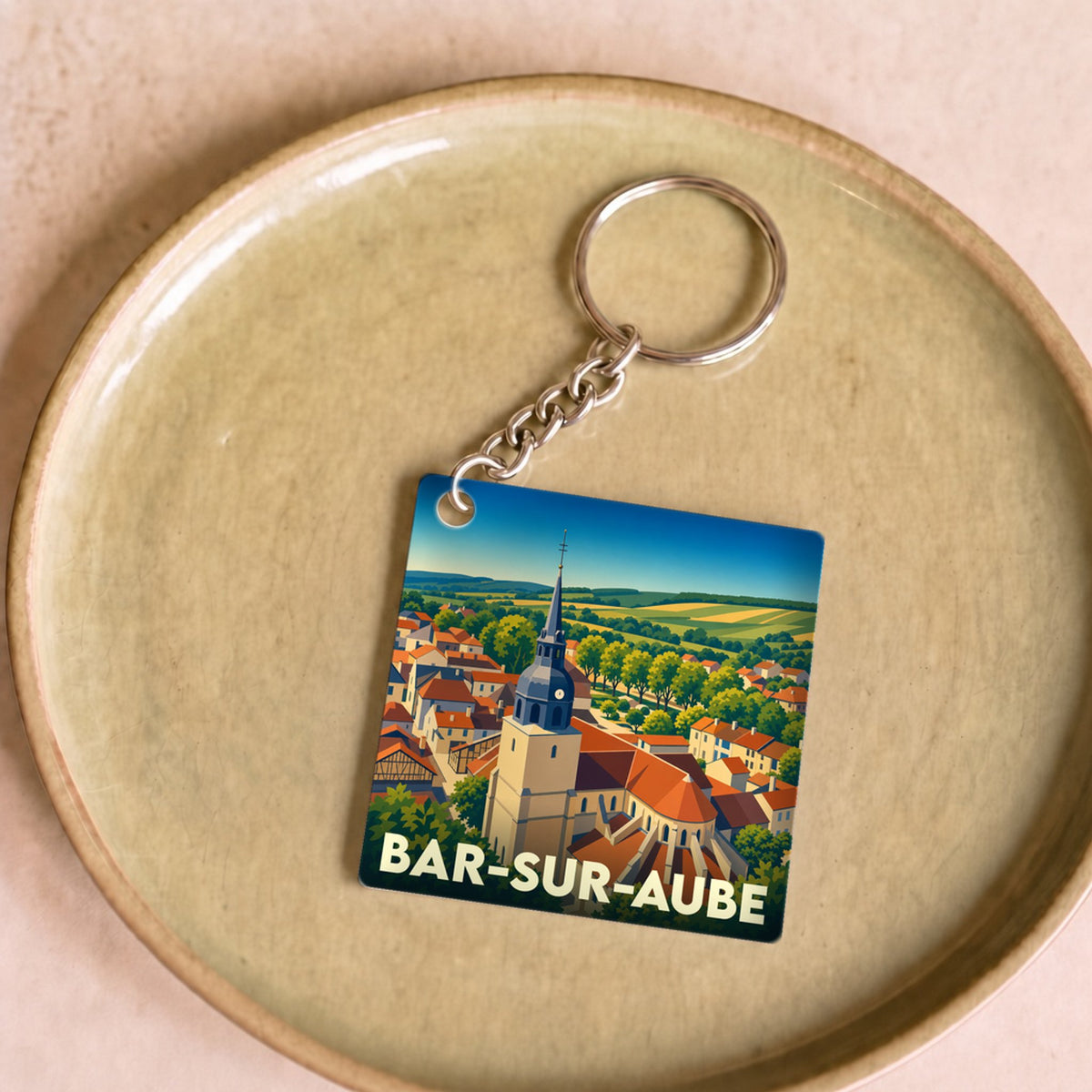 Porte-clés souvenir de la ville de Bar-sur-Aube avec une illustration stylisée de son église et de ses paysages.