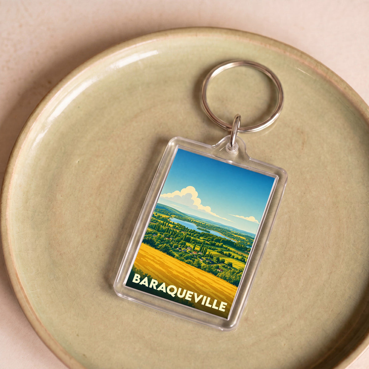 Porte-clés souvenir de la ville de Baraqueville avec une illustration stylisée de son paysage rural.