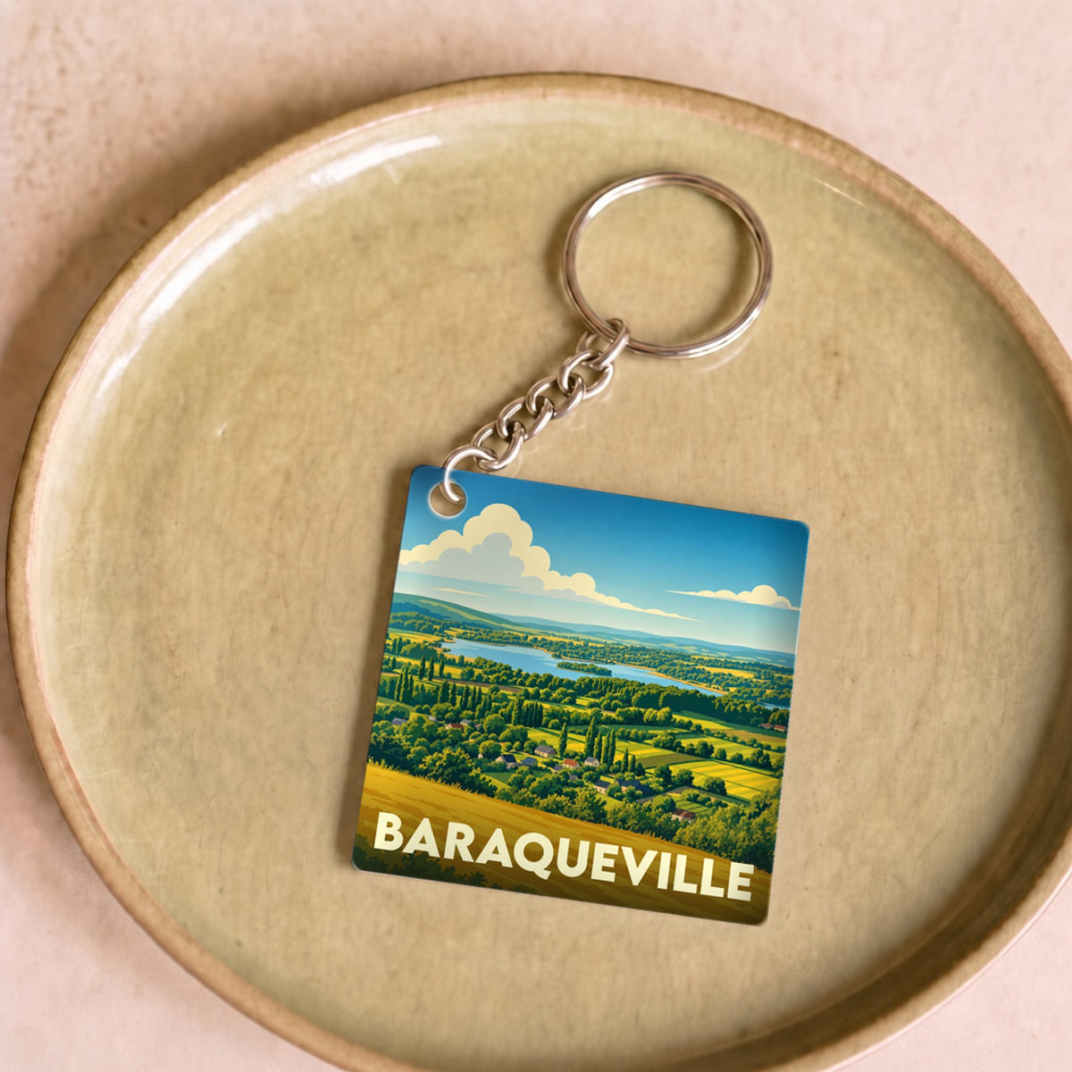 Porte-clés souvenir de la ville de Baraqueville avec une illustration stylisée de son paysage rural.