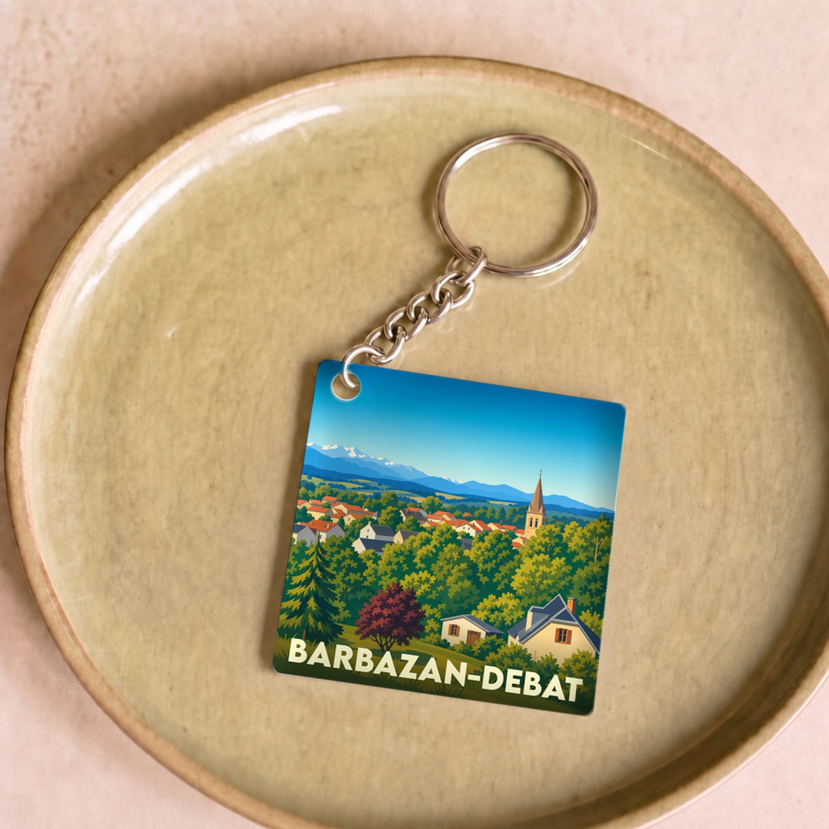 Porte-clés souvenir de la ville de Barbazan-Debat avec une illustration stylisée d'un paysage de montagne.