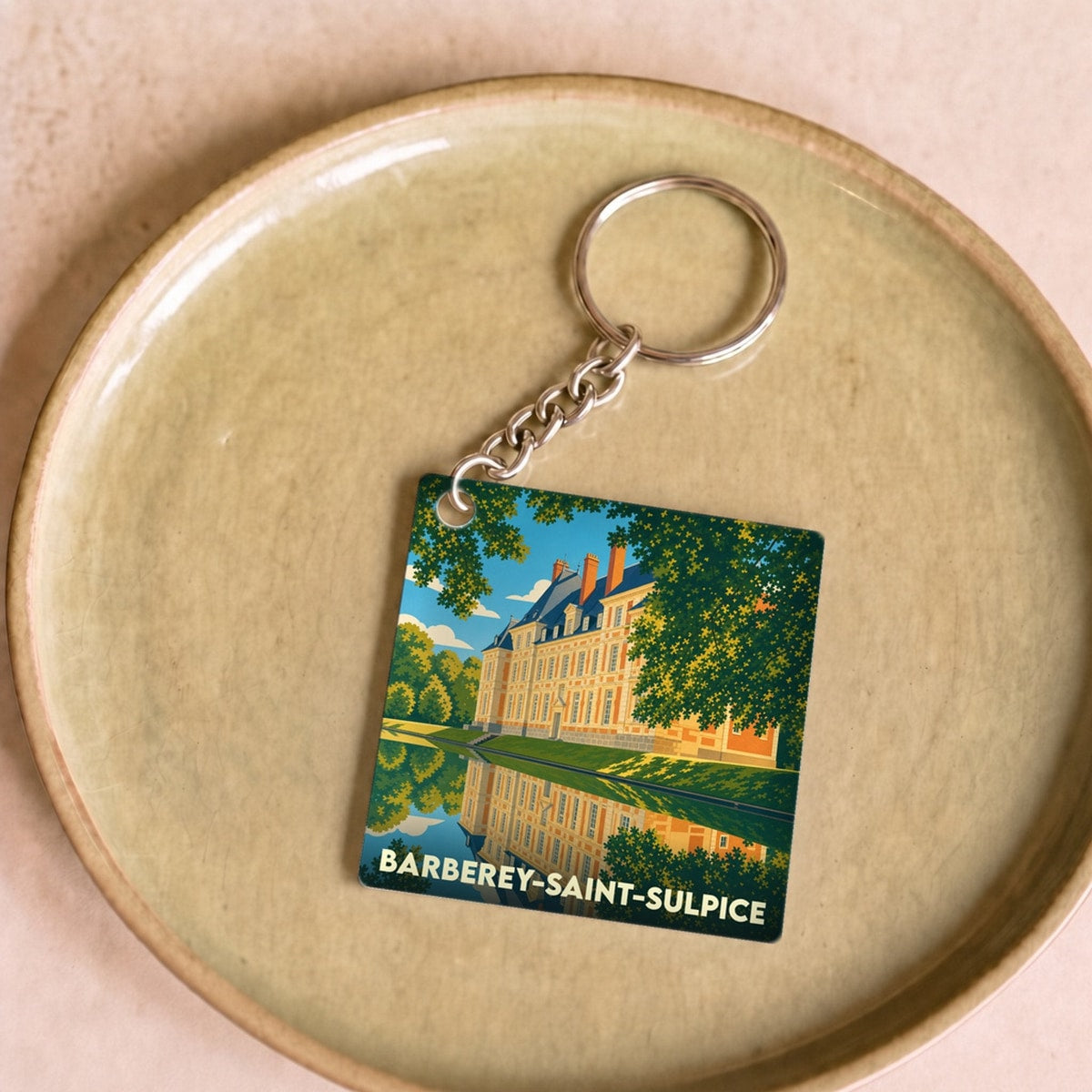 Porte-clés souvenir de la ville de Barberey-Saint-Sulpice avec une illustration stylisée de son château se reflétant dans l'eau.