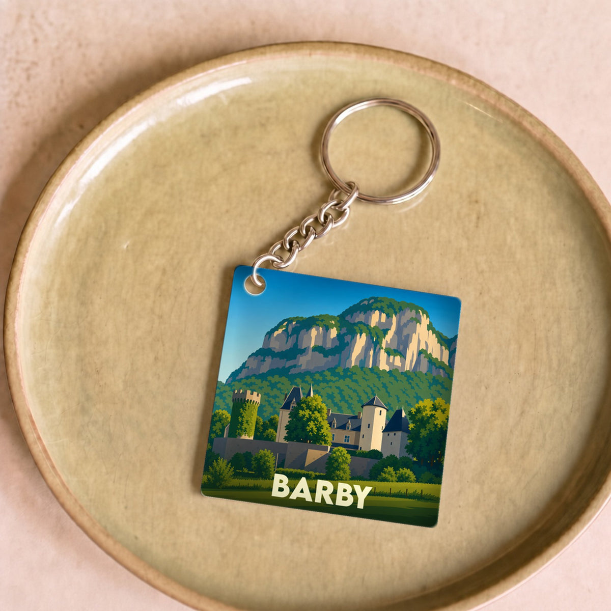 Porte-clés souvenir de la ville de Barby avec une illustration stylisée de son château et des montagnes environnantes.
