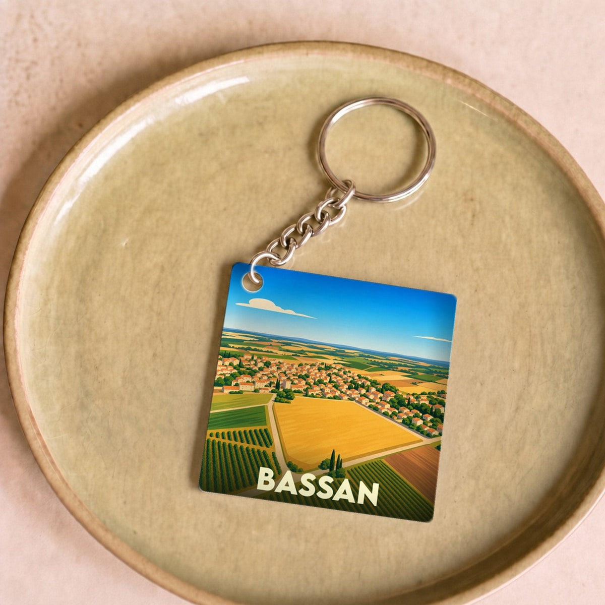 Porte-clés souvenir de la ville de Bassan avec une illustration stylisée de ses paysages et vignobles.