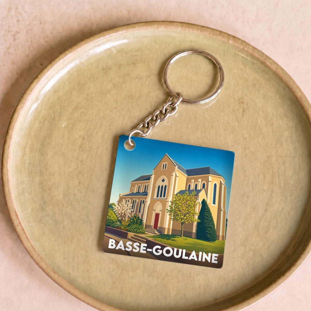 Porte-clés souvenir de la ville de Basse-Goulaine avec une illustration stylisée de son église.