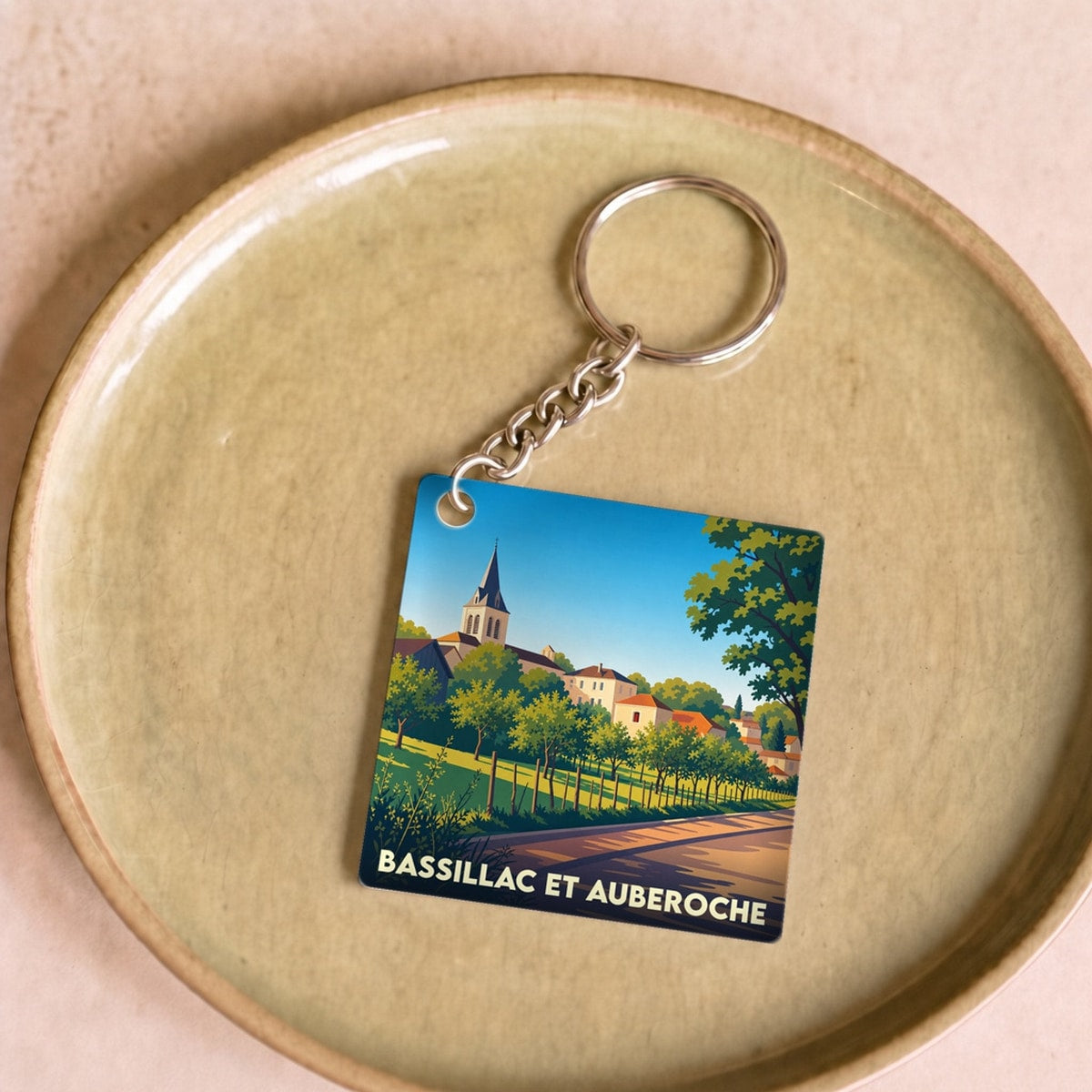 Porte-clés souvenir de la commune de Bassillac et Auberoche avec une illustration stylisée du village.