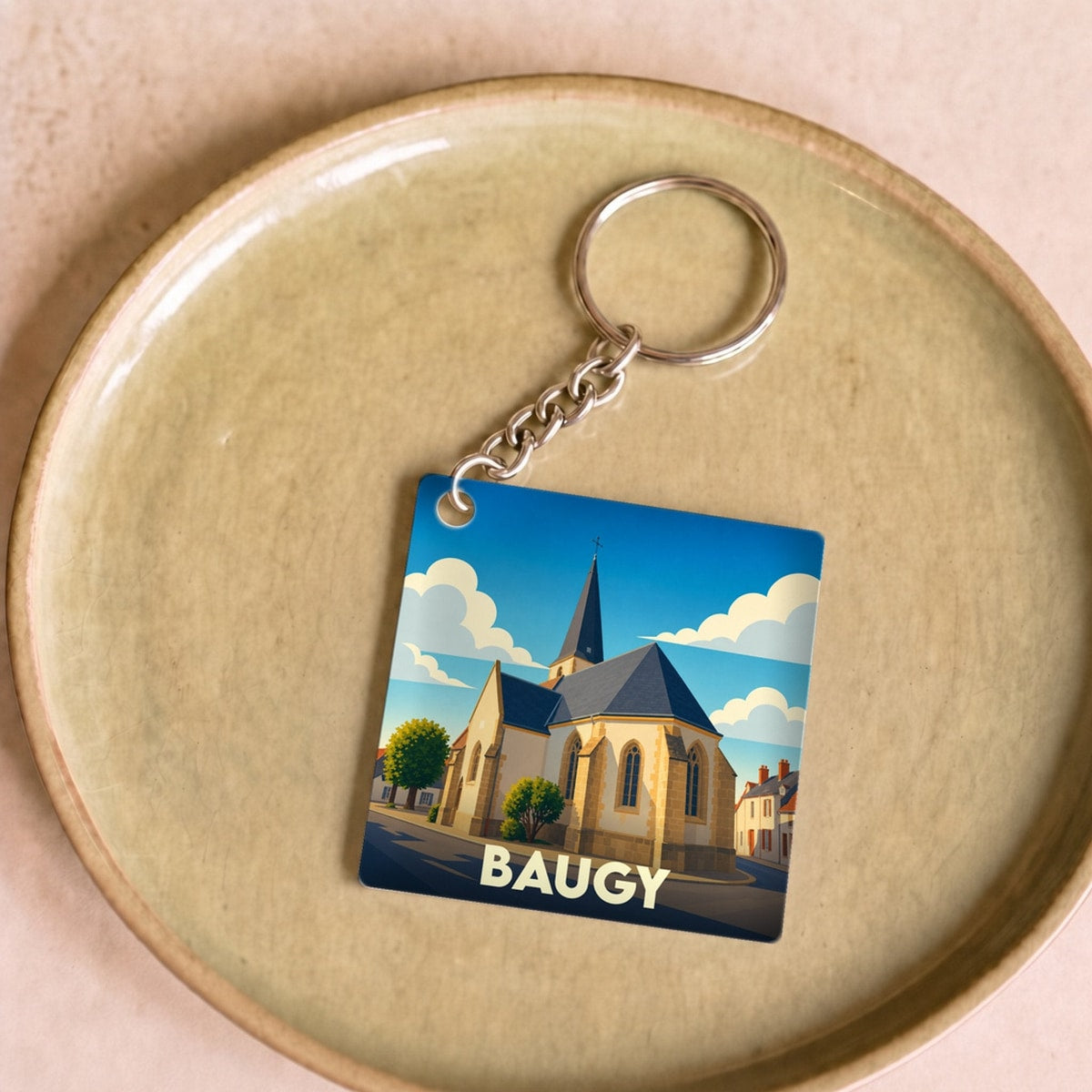 Porte-clés souvenir de la ville de Baugy avec une illustration stylisée d'une église sous un ciel bleu.