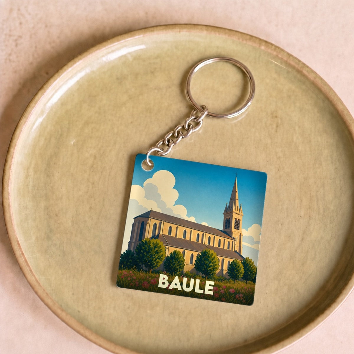 Porte-clés souvenir de la ville de Baule avec une illustration stylisée d'une église.