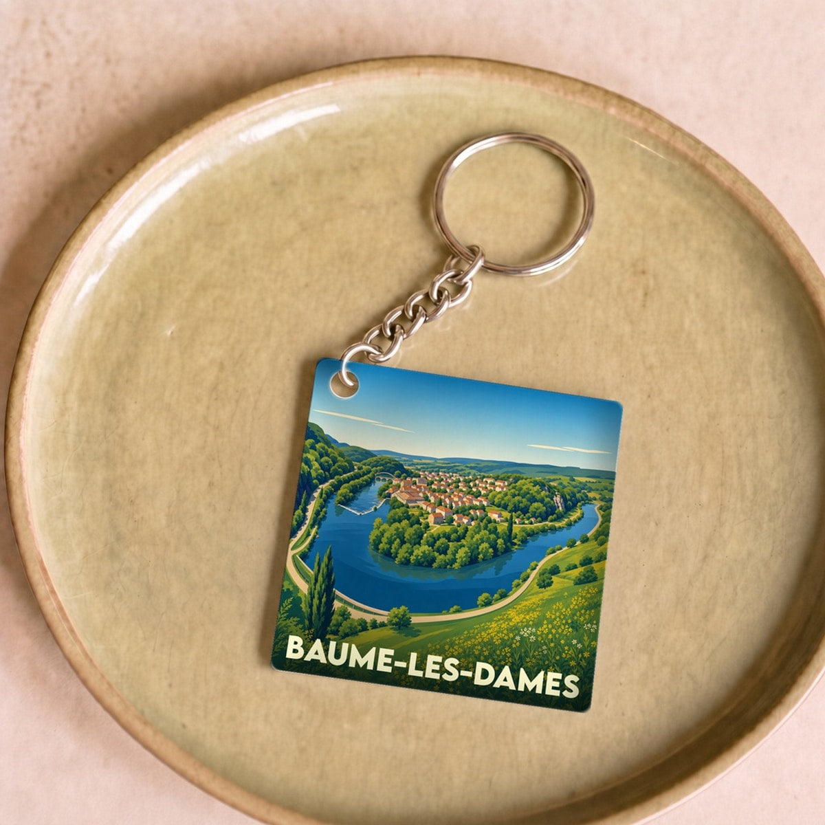 Porte-clés souvenir de la ville de Baume-les-Dames avec une illustration stylisée d'un méandre de rivière.